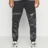 Nike Performance PANT TAPER CAMO - Tracksuit Bottoms - Black/coconut Milk